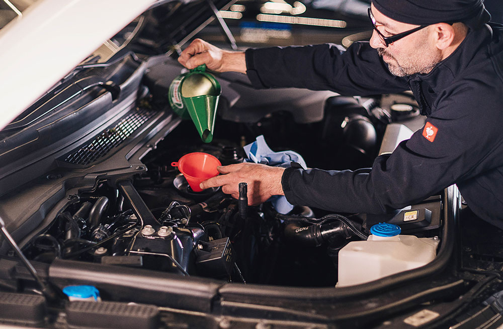 oelwechsel Mechaniker füllt das Öl nach